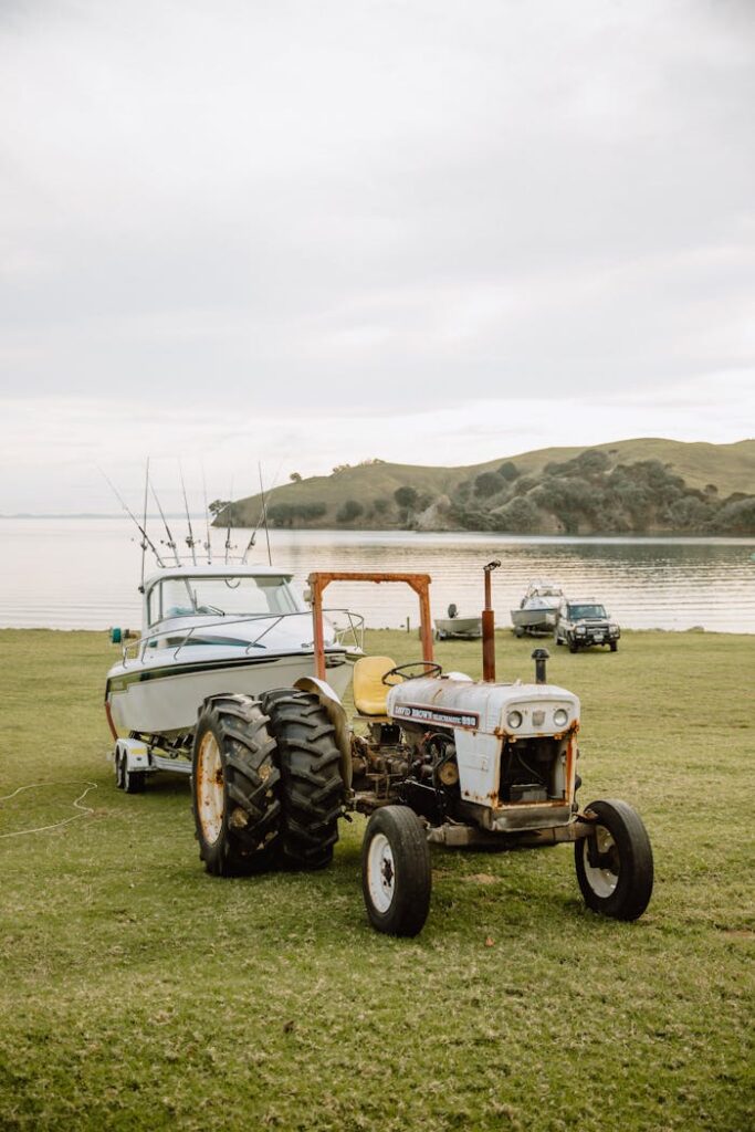 A tractor towing a motorboat on a grassy meadow near the picturesque coast of Kereta, Waikato.